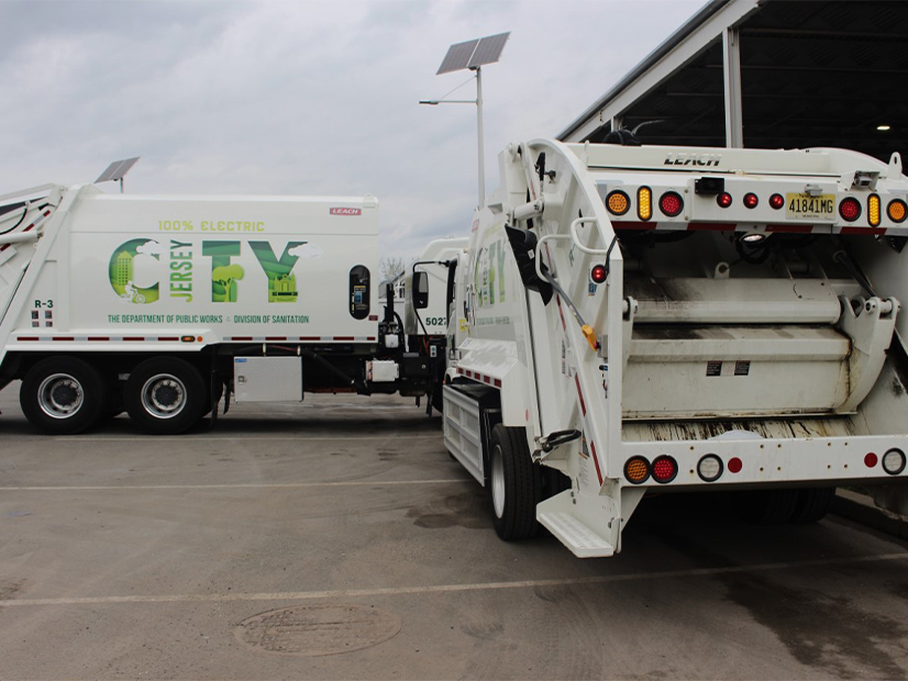 Two of Jersey City's five new electric garbage trucks, all of which will be powered by solar panels on the roof of the city's Department of Public Works.