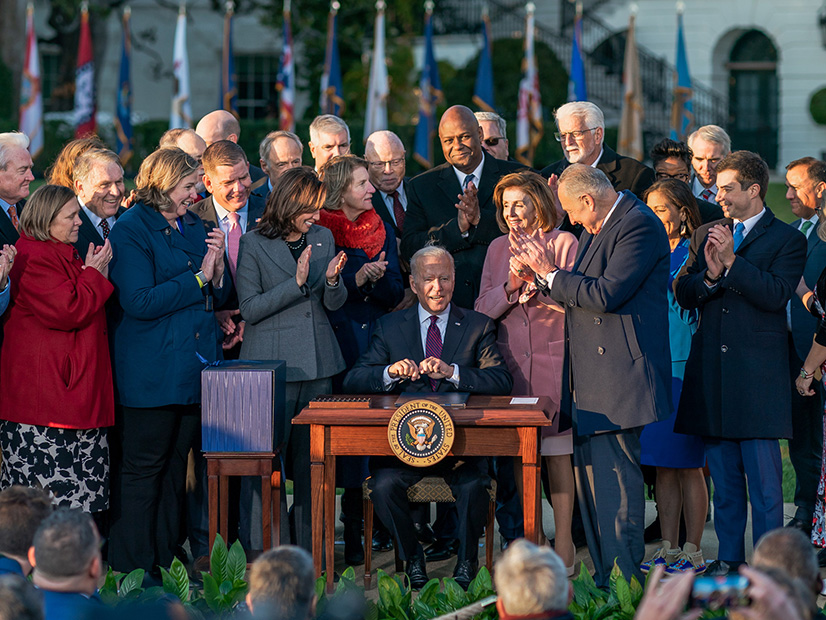 President Biden signs the Infrastructure Investment and Jobs Act, surrounded by congressional supporters