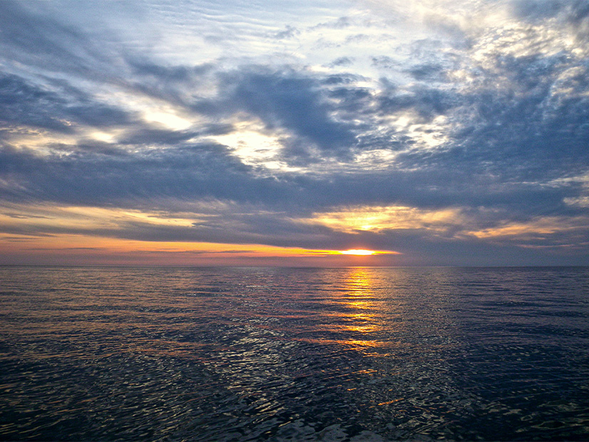 A new report suggests New York not rush to build wind turbines in the waters of Lake Ontario, shown here at sunset.