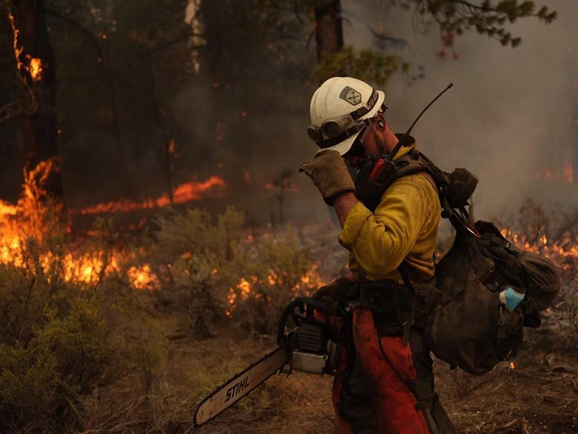 A firefighter takes a break while using a chainsaw along a Dixie Fire line.