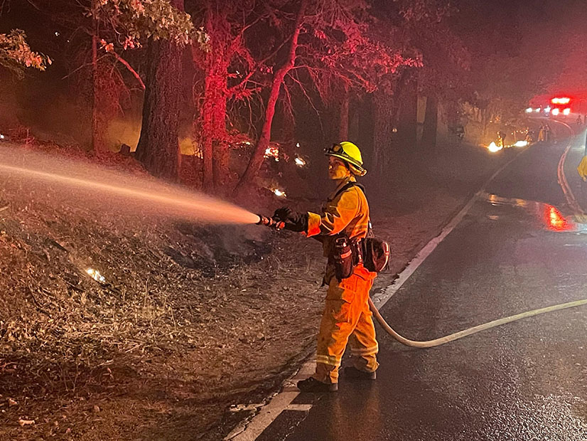 A firefighter hoses down 'hot spots' on the Dixie Fire Sunday.