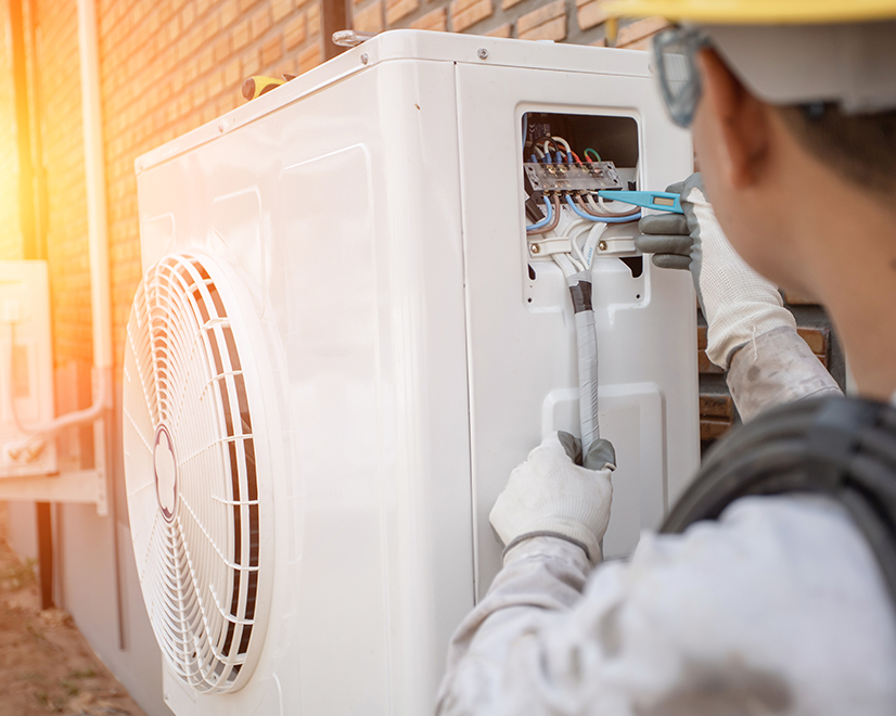 <div>An installer adjusts an electric heat pump.</div>