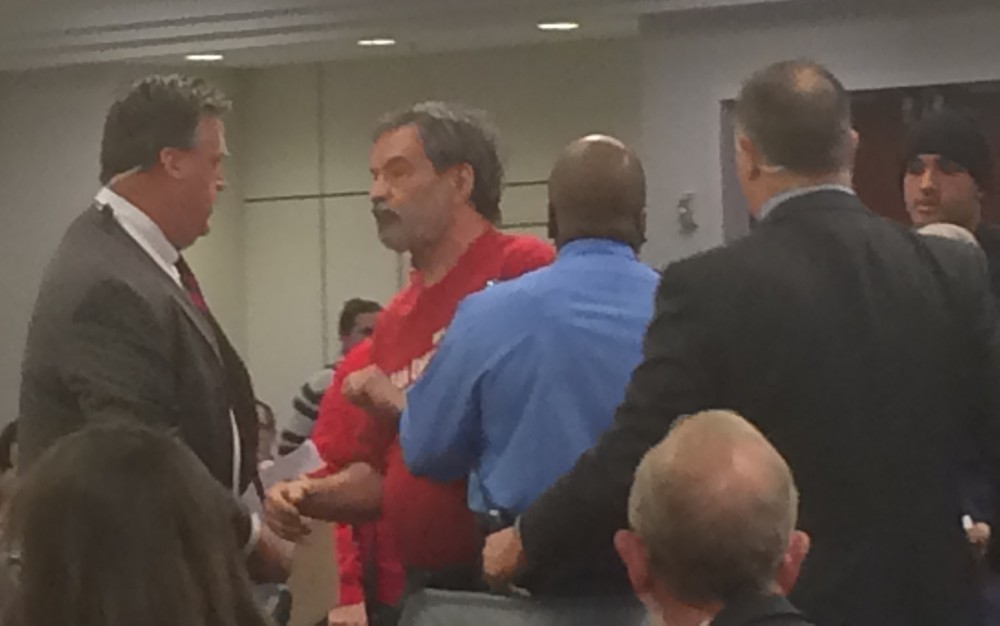 Protester briefly resists security guards attempting to escort him out of FERC meeting. 