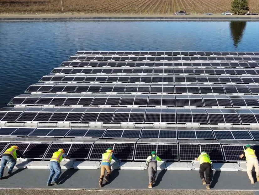 Workers push solar panels onto pond at Healdsburg, Calif., water treatment plant. 