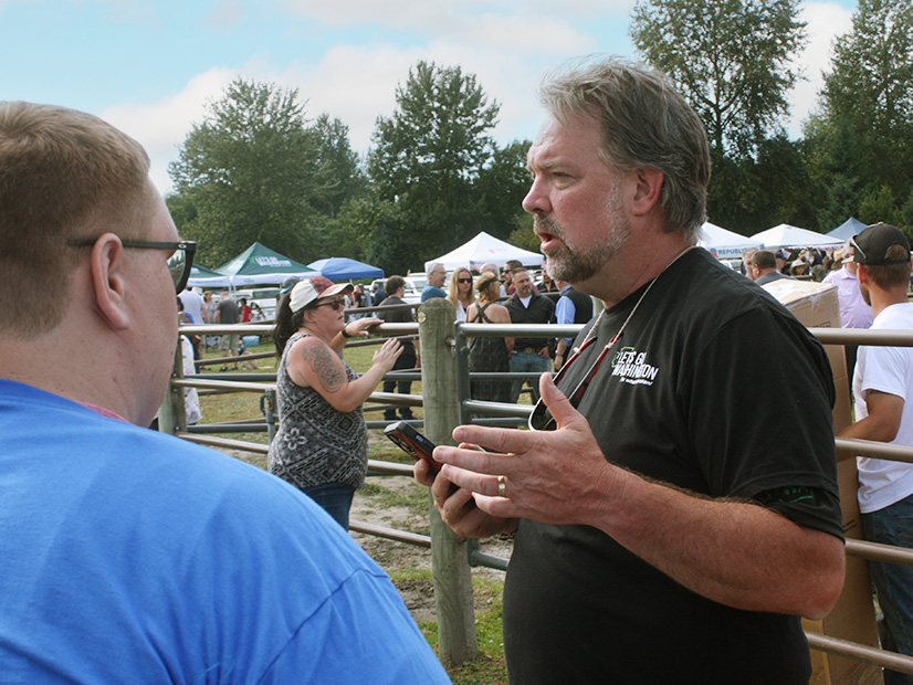 Brian Heywood, head of an effort to petition Washington's Legislature to repeal the state's cap-and-trade law, talks with supporters at a Republican political festival in the Seattle suburbs. 
