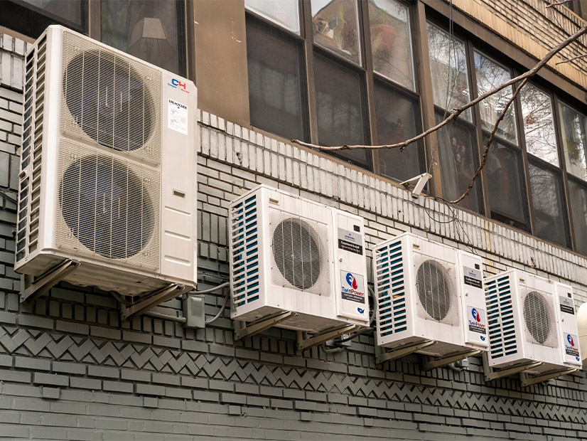 Heat pumps line the wall of a New York City apartment house.