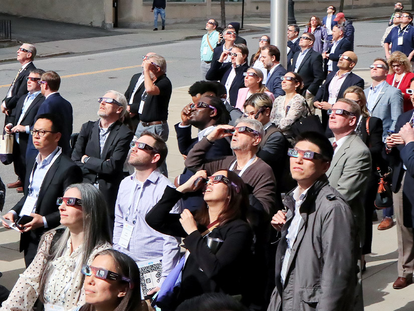 Attendees at the New York Energy Conference take a break to look at the eclipse in Albany, N.Y., on April 8.