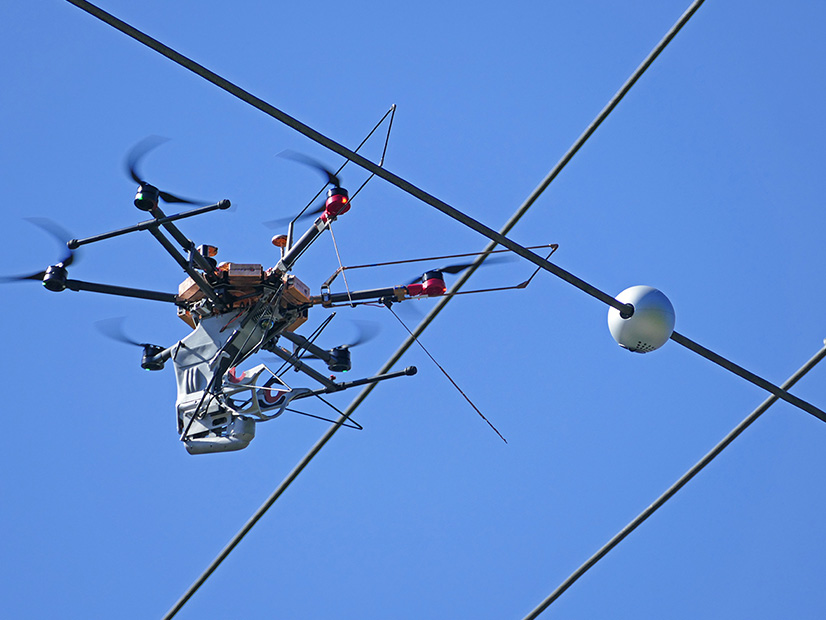 A Heimdall drone installing a monitoring device on a PSE transmission line. A Heimdall drone installing a monitoring device on a PSE transmission line.