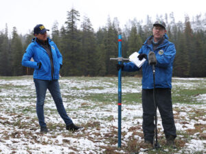 A California DWR manager measures the snowpack level at Phillips Station on April 1. In an average year, snowpack is about five feet high at this location on April 1, measuring up to the second red line on the blue metal pole in the photo. But in 2026, there was nothing to measure — only grass. A California DWR manager measures the snowpack level at Phillips Station on April 1. In an average year, snowpack is about five feet high at this location on April 1, measuring up to the second red line on the blue metal pole in the photo. But in 2026, there was nothing to measure — only grass.